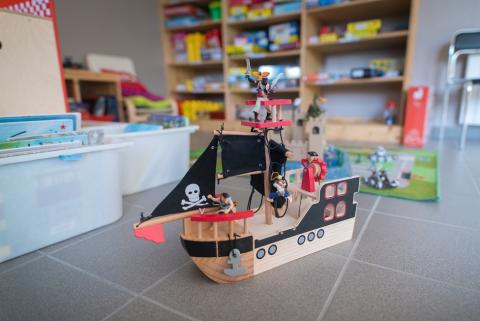 Un bâteau de pirates au premier plan, des étagères remplies de jeux au second plan