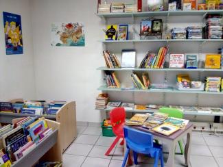 L'espace jeunesse de la bibliothèque de Tours sur Meymont avec des bacs à albums un etable et des petites chaises colorées