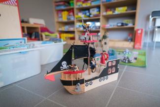Un bâteau de pirates au premier plan, des étagères remplies de jeux au second plan