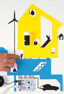 une maison en collage, un doigt qui appuie sur le collage et une carte électronique