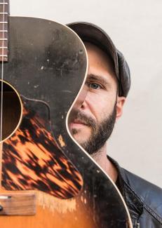 portrait du musicien à moitité caché derrière sa guitare