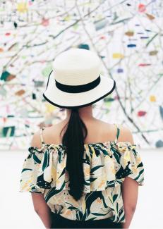 une femme portant un chapeau et qui regarde un tableau