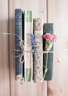 quatre livres rassemblés par une ficelle et décorés de fleurs séchées