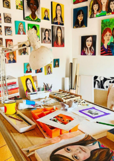 une photo de l'atelier de Géraldine Nardoux Reyne, avec des portraits, très colorés, en cours de création, et d'autres accrochés aux murs
