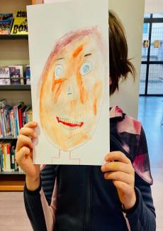 photo d'un enfant ayant réalisé son autoportrait, le tenant devant son visage