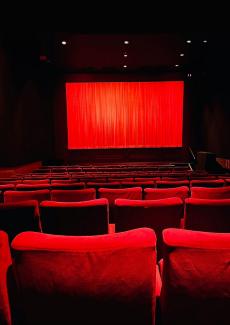 photo d'une salle de cinéma avec un écran et des fauteuils rouges