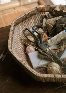 des bobines de fil et une paire de ciseaux dans une panière tressée