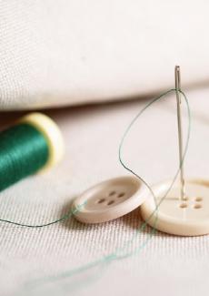photographie de boutons avec du fil et une aiguille à coudre