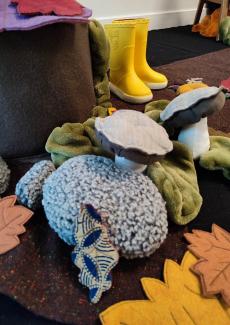 une photo de l'installation, éléments d'automne, bottes jaunes, raconte-tapis, feuilles en tissu...